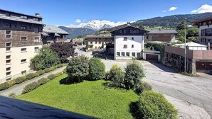 Ein Wohngebiet mit Gebäuden, blauem Himmel und schneebedeckten Bergen im Hintergrund.