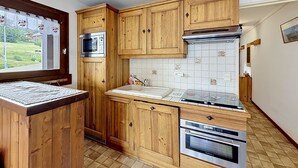 Eine Küche mit Holzausstattung, einer Mikrowelle, einer Fliesenrückwand und einem Fenster mit Blick.