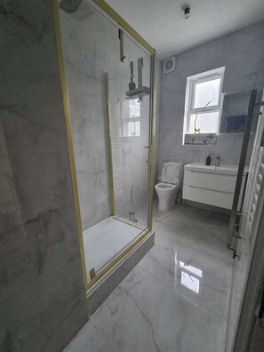 A bathroom with a glass-enclosed shower, a toilet, and a sink. - Spacious Apartment Sleeps 2 With Parking, Newly Refurbished (Ilford)
