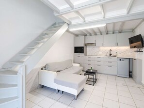Ein kompakter Wohnbereich mit Treppe, Küchenzeile und einer Couch.