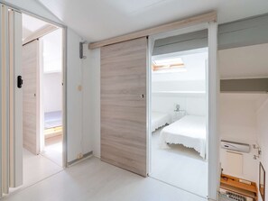 Ein Zimmer mit einer Schiebetür, einem Bett, einem Dachfenster und einer kleinen Schreibtischzeile.