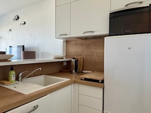 Eine moderne Küche mit weißen Schränken, einer Holzarbeitsplatte, einer Spüle, einer Kaffeemaschine und einem Kühlschrank.