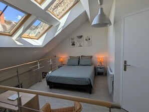Ein Schlafzimmer mit Oberlicht, einem Bett, Nachttischen und einer Tür.