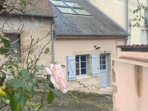 Un bâtiment doté d’un toit en pente, d’un petit porche et d’une seule fenêtre avec des volets.