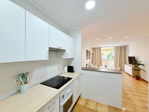 A modern kitchen with white cabinets, a black induction cooktop, and a small countertop area.