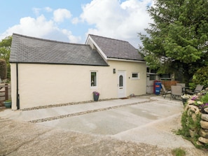 A single-story building with a sloped roof, a small porch, and a door. - Ty Loti (Caernarfon)