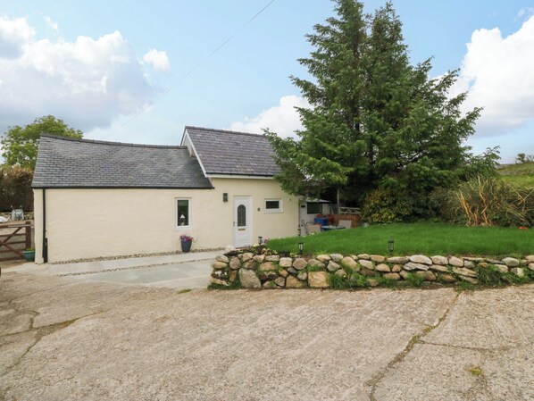 A two-story house with a stone wall and a grassy yard. - Ty Loti (Caernarfon)