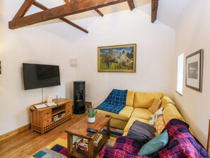 Uma sala de estar com sofá, mesa de centro, televisão, lareira e um quadro na parede.
