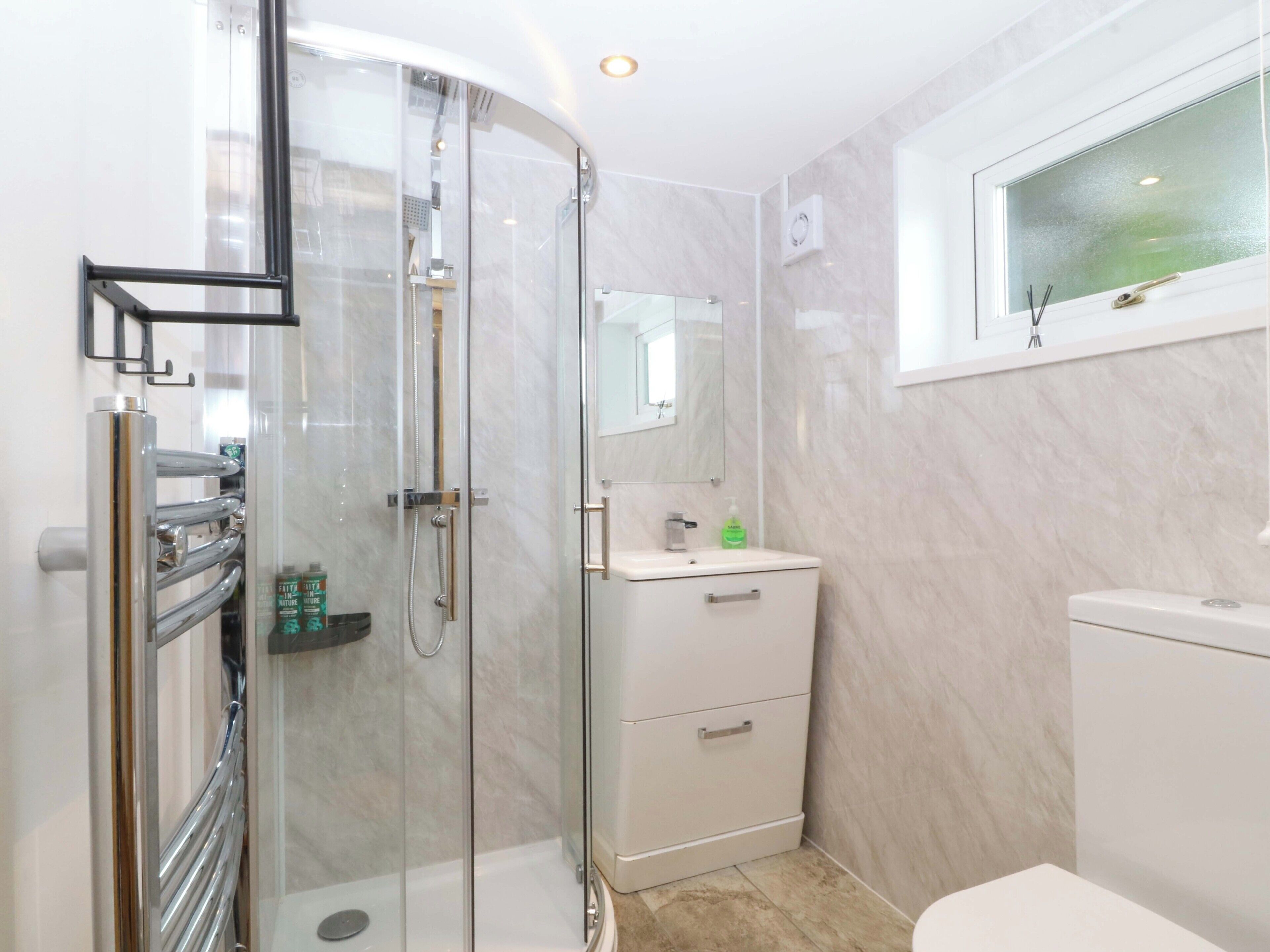 A modern bathroom with a glass shower enclosure, a white sink, and a toilet.