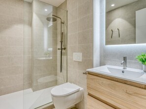 Ein modernes Badezimmer mit einer gläsernen Duschkabine, einer weißen Toilette und einem Holzwaschtisch.
