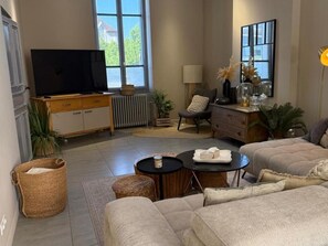 Ein Wohnzimmer mit Fernseher, Sofa, Couchtisch und Blick ins Freie.