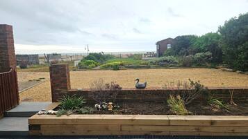 A garden with a swan statue, a wooden bench, and a brick wall.