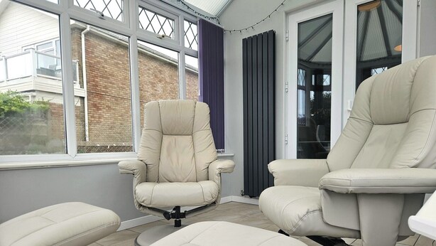 A conservatory with two beige leather chairs and a matching ottoman, large windows, and a grey radiator. - Beach Horizon - ground floor flat with patio boasting views to sea (Pevensey Bay)