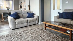 A modern living room with a sofa, coffee table, and a rug. - Beach Horizon - ground floor flat with patio boasting views to sea (Pevensey Bay)