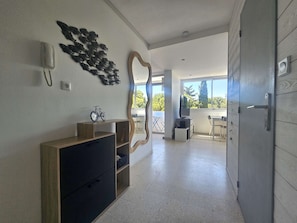 Ein modernes Interieur mit einem Holzschrank, einem an der Wand befestigten Telefon, Fisch-Wandbildern, einem Spiegel und Blick ins Freie.