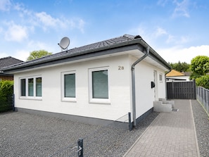 Ein eingeschossiges Gebäude mit weißer Fassade, einer Satellitenschüssel und der Hausnummer 2a an der Seite.