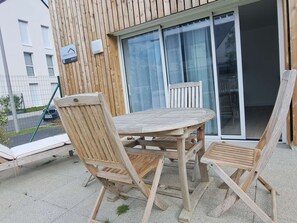 Eine Holzterrasse mit rundem Tisch und vier Stühlen, einer Schiebetür und einem Schild mit der Aufschrift 'HEMISPHERE'.