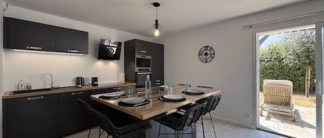 A modern kitchen with dark cabinetry, a wooden dining table, and black chairs.