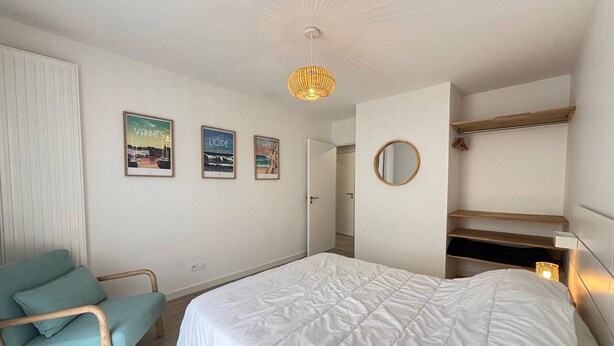 A bedroom with a bed, a chair, a wardrobe, and a mirror. - Comfortable apartment with parking - 4/5 guests (Carnac)