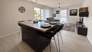 A modern kitchen with a central island, dining area with chairs, and a living space with a sofa and a coffee table. - Comfortable apartment with parking - 4/5 guests (Carnac)