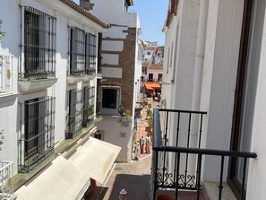 A narrow street with buildings on either side, a balcony with a railing, and a small outdoor seating area. - Quiet apartment with balcony in the heart of Marbella (Marbella)