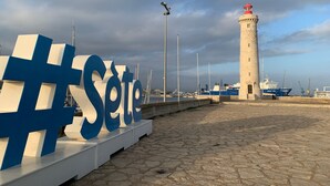 A stone-paved promenade with a large illuminated sign reading "Sete", a lighthouse, and a blue ship docked nearby. - Apartment with AC, parking - 4 guests (Sète)