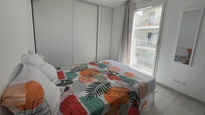 A bedroom with a bed, a wardrobe, a balcony with a view, and a hanging light fixture. - Apartment with AC, parking - 4 guests (Sète)