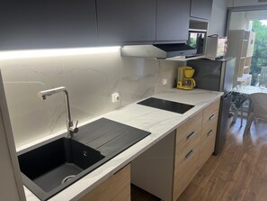 Eine moderne Küche mit einer Spüle, einem Kaffeeautomaten und Blick ins Freie.