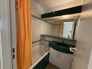 Ein Badezimmer mit Badewanne, Waschbecken, Spiegel und Duschvorhang.