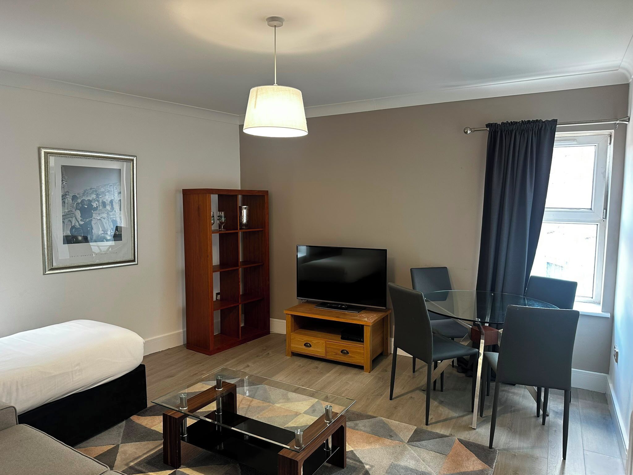 Un salon moderne comprenant un canapé, un téléviseur, un meuble en bois et un coin repas avec des chaises.