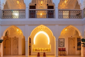 A multi-level interior with arched doorways, a central seating area, and a balcony with ornate railings.