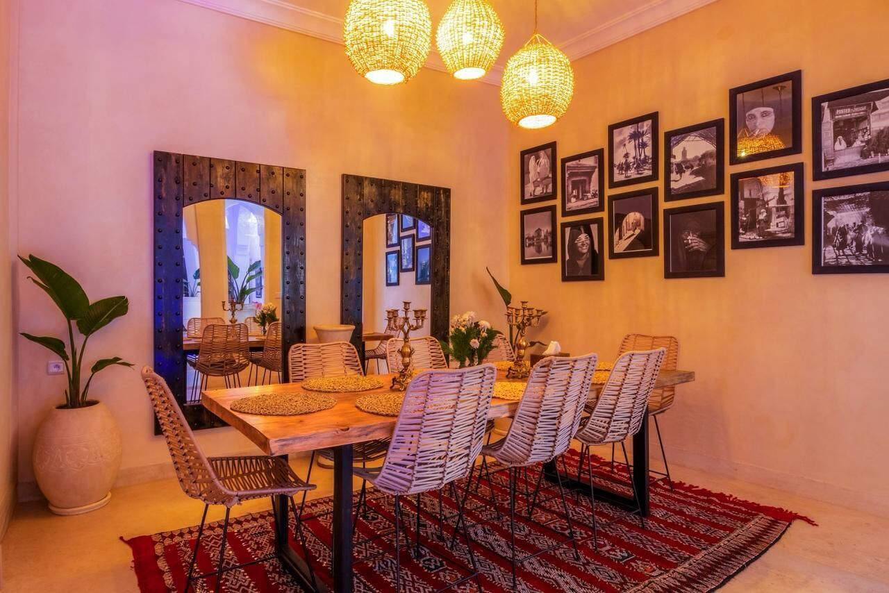 A dining area with a wooden table, patterned chairs, and a red rug.