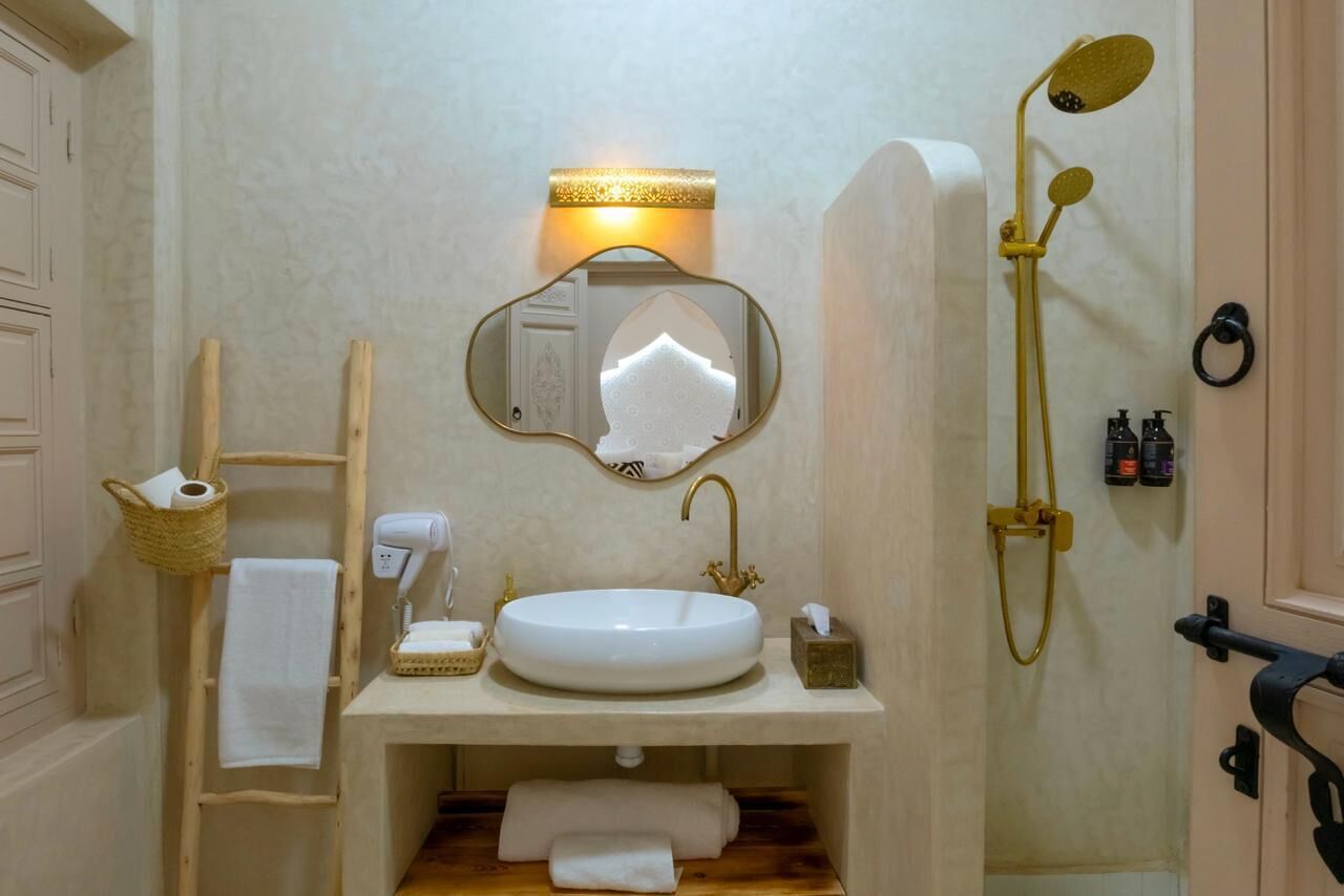 A bathroom with a sink, mirror, towel rack, and shower.