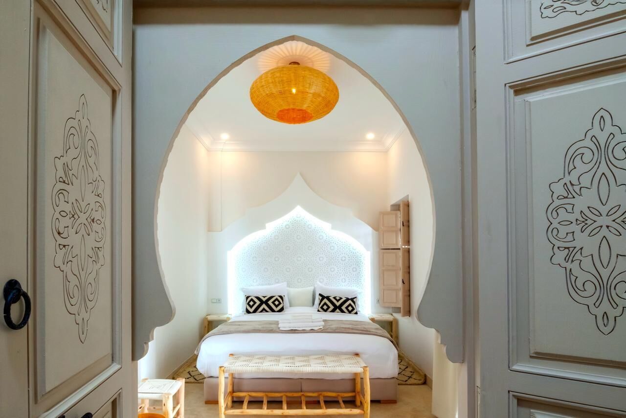 Une chambre à coucher avec un grand lit, un luminaire suspendu et un arc décoratif.