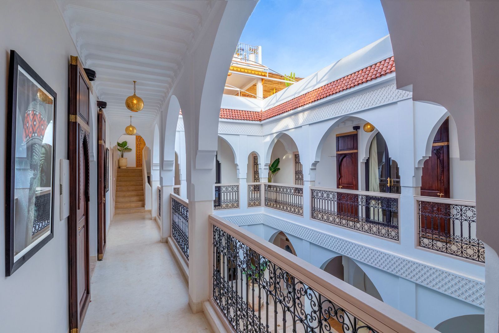 A covered corridor with arches, a staircase, and balconies with railings.