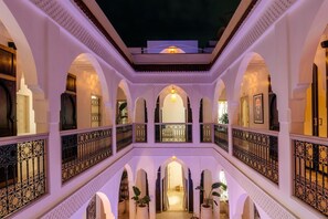 A multi-level courtyard with arches and balconies, featuring a central open space and potted plants.