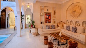 A spacious living room with a white sofa set, a coffee table, and a large painting on the wall. - Riad Dar Noa Marrakech (Marrakech)