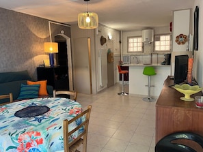 Ein kleiner Wohnraum mit Bett, Esstisch, Küchenzeile und Barhocker.