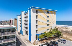 A multi-story hotel with balconies, a beach view, and a parking area.