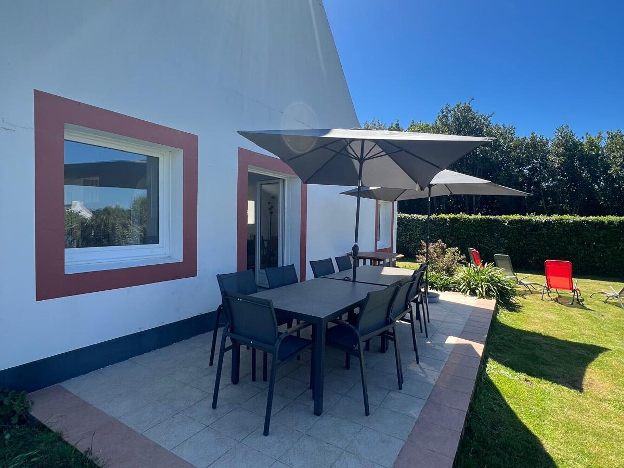 A patio with a table and chairs, a large umbrella, and a red chair.