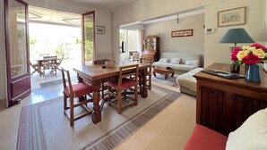 Un comedor con una mesa y sillas de madera, un sofá y un aparador con una lámpara.