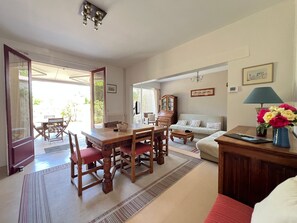Ein Essbereich mit Holztisch und Stühlen, einer Couch und einem Schrank mit Lampe.