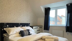 A bedroom with a brick-patterned headboard, a window with curtains, and a neatly made bed. - The Coach-House, Lincoln Central + Parking, walking distance to all attractions (Lincoln)
