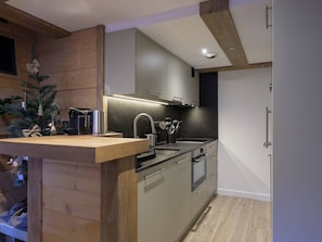 Eine moderne Küche mit Holzausstattung, einem eingebauten Ofen und einer Spüle aus Edelstahl.