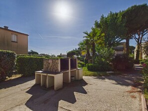A courtyard with a concrete bench, a stone planter, and a clear sky. - Apartment with pool - 6 guests (Le Grau d'Agde)