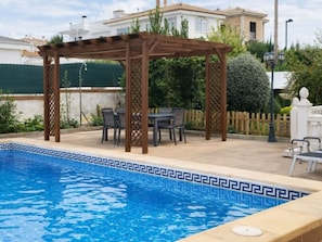 A pool with a geometric tile pattern, a wooden pergola, and outdoor furniture. - Comfortable house with AC - 10 guests (Granada)