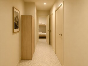A corridor with a wooden wardrobe, a framed picture on the wall, and a bunk bed in the distance. - Authentic Vercors Getaway – Ski, Hiking, Cycling – Slopeside Apartment for 6 (Villard-de-Lans)