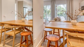 A modern kitchen with white cabinets, a wooden dining table, and bar stools. - Modern apartment near the port - 4 guests (Estepona)