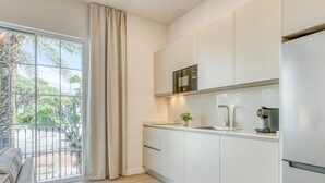 A modern kitchen with a built-in oven, a coffee machine, and a view of a balcony with a palm tree. - Modern apartment near the port - 4 guests (Estepona)