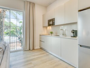 Eine moderne Küche mit Einbauofen, einer Kaffeemaschine und Blick auf einen Balkon mit einer Palme.